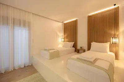 a white room with two beds and a window at Ikia Seascape At Stegna in Archangelos