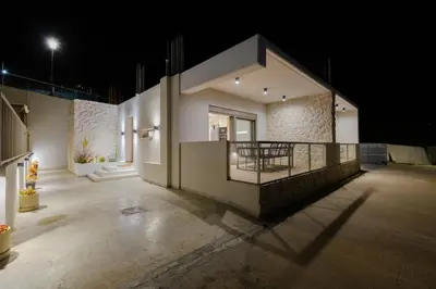 a large building with a balcony at night at Ikia Seascape At Stegna in Archangelos