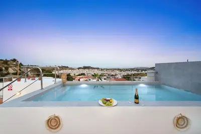 a villa with a swimming pool and a bottle of wine at Afandou Panorama Apartment in Afantou