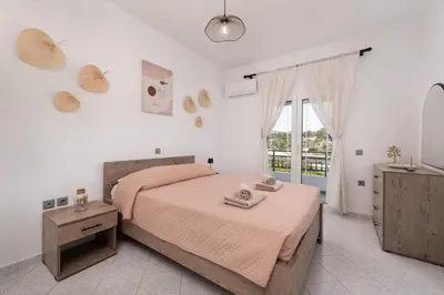 a white bedroom with a bed and a window at Afandou Panorama Apartment in Afantou