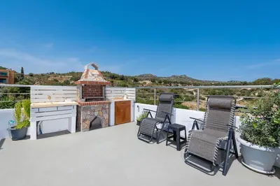 a balcony with two chairs and a grill at Afandou Panorama Apartment in Afantou