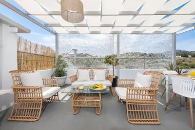 a patio with wicker chairs and a table with a glass tableasteryasteryastery at Afandou Panorama Apartment in Afantou