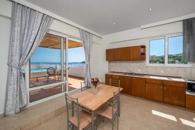 a kitchen with a table and a view of the ocean at Stegna Sunrise Suite Sleeps 4 Pool in Archangelos
