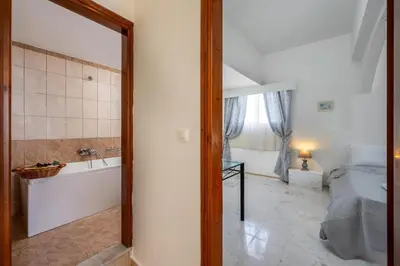 a bathroom with a tub and a bedroom with a bed and a bath tub at Stegna Sunrise Suite Sleeps 4 Pool in Archangelos