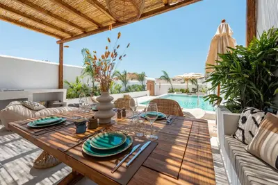 a wooden table with plates and glasses on a patio at CasaCarma III, private pool, boho design, central in Lachania