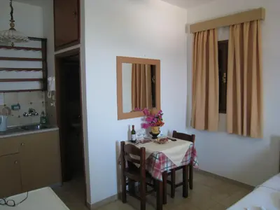a dining room with a table and chairs and a kitchen at Eleftheria Lindian Studios I in Líndos