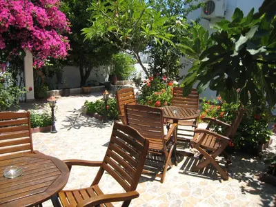 a group of wooden chairs and tables with flowers at Eleftheria Lindian Studios I in Líndos