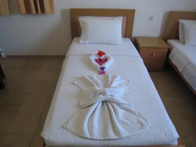 a hotel room with a white bed with a dress on it at Eleftheria Lindian Studios I in Líndos