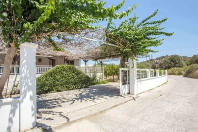 a white fence in front of a house with trees at Villa Hercules in Kremasti