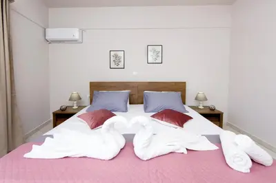 a bed with white sheets and red pillows at Palm Square Appart in Ialyssos
