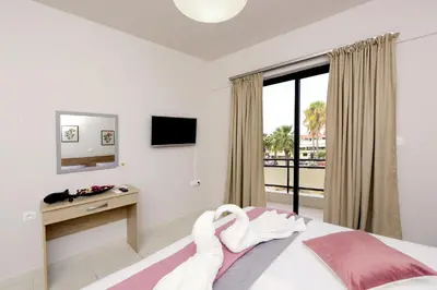 a bedroom with a bed and a desk and a window at Palm Square Appart in Ialyssos