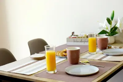 a wooden table with orange juice and food on it at Palm Square Appart in Ialyssos