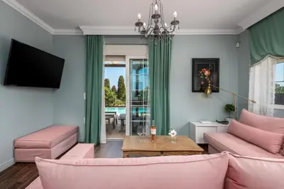 a living room with pink furniture and a chandelier at Cypress View Boutique Villa in Asgourou