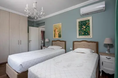 two beds in a room with blue walls and a chandelier at Cypress View Boutique Villa in Asgourou