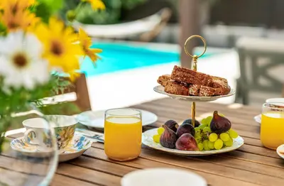 a table with a plate of food and orange juice at Cypress View Boutique Villa in Asgourou