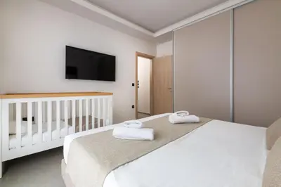 a white bedroom with a crib and a tv at Mirena Luxury Living-Casa di Maria in Afantou
