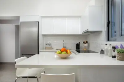 a white kitchen with a bowl of fruit on a counter at Aetheria Central Apartments in Rhodes Town