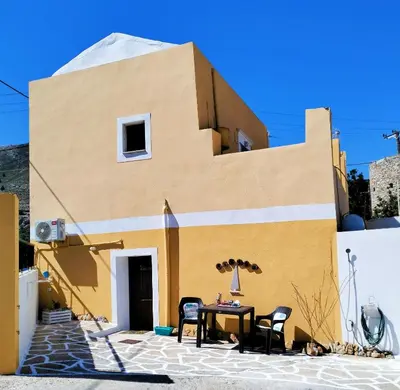 a building with a table and chairs in front of it at The Mill House Stella in Symi