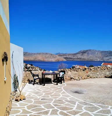 a patio with a table and chairs and a lake at The Mill House Stella in Symi