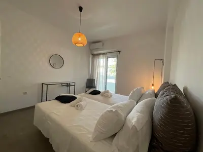 a bedroom with two beds with white sheets and a couch at MV central in Rhodes Town