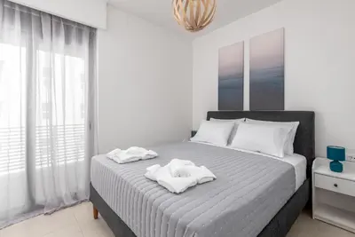a white bedroom with a bed with towels on it at Rhodes Retreat & Getaway Apartments in Rhodes Town