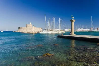 a dock with a statue in the water with boats at Rhodes Retreat & Getaway Apartments in Rhodes Town