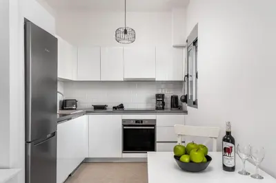 a kitchen with white cabinets and a bowl of apples at Rhodes Retreat & Getaway Apartments in Rhodes Town
