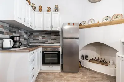 a kitchen with white cabinets and a stainless steel refrigerator at Amalia's Traditional Home in Paradisi in Paradeísion