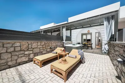 a patio with two benches and a stone wall at Kimia Luxury Apartments in Kolimbia