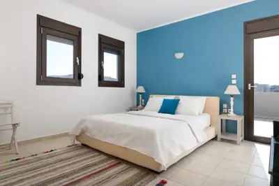 a bedroom with a large bed with blue walls and windows at Villa Athena with Private Pool and Seaview in Líndos