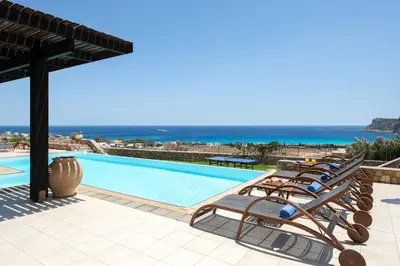 a group of lounge chairs next to a swimming pool at Villa Athena with Private Pool and Seaview in Líndos