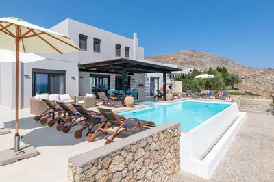 a pool with chairs and an umbrella next to a house at Villa Athena with Private Pool and Seaview in Líndos
