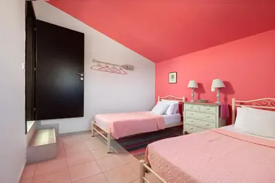 a room with two beds with pink walls and a tv at Villa Athena with Private Pool and Seaview in Líndos