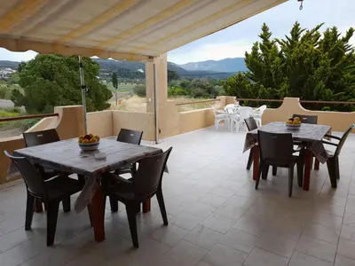 a patio with tables and chairs and a view of the mountains at Green View Appartment (Thanasis 2) in Kalavárda