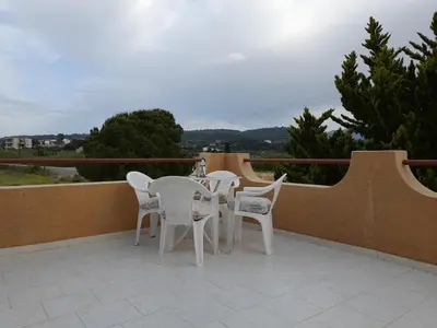 a patio with white chairs and tables on a balcony at Green View Appartment (Thanasis 2) in Kalavárda