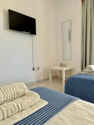 a room with two beds and a tv on the wall at Green View Appartment (Thanasis 2) in Kalavárda