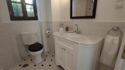 a white bathroom with a toilet and a sink at Marietta's House in Rhodes Town