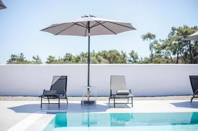 two chairs and an umbrella next to a pool at VillaPhysis with Private Pool in Lardos