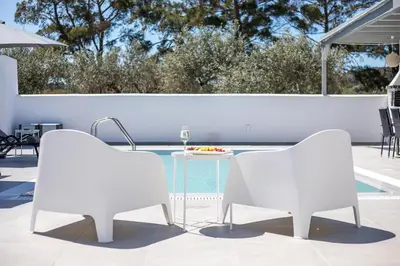 two white chairs and a table next to a pool at VillaPhysis with Private Pool in Lardos