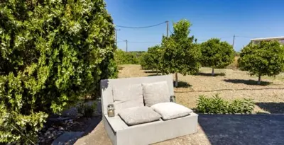 a white couch sitting in the middle of a yard at Garden View Appartment (Thanasis) in Kalavárda