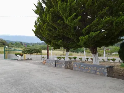 two trees in a park next to a fence at Garden View Appartment (Thanasis) in Kalavárda