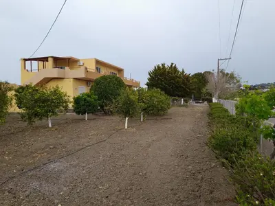 a house with trees in front of a dirt road at Garden View Appartment (Thanasis) in Kalavárda