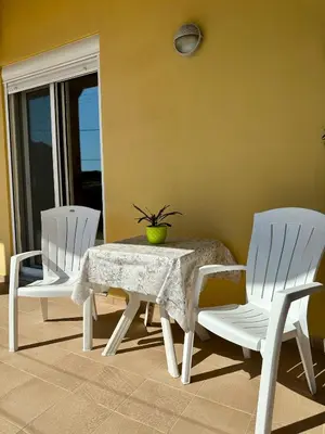 two white chairs and a table with a potted plant on it at Garden View Appartment (Thanasis) in Kalavárda