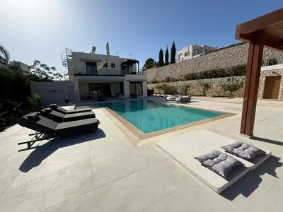 a swimming pool with two loungers in front of a house at Villa Chrysa Rhodes with Heated Pool in Afantou