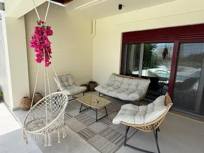 a porch with a swing and chairs and a table at Villa Chrysa Rhodes with Heated Pool in Afantou