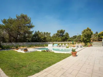 a backyard with a swimming pool with chairs and trees at Holiday Home near Beach in Afandou in Koskinou