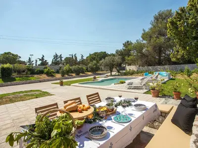 a table with plates of food on it next to a pool at Holiday Home near Beach in Afandou in Koskinou