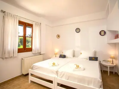 a white bedroom with a large white bed and a window at Holiday Home near Beach in Afandou in Koskinou