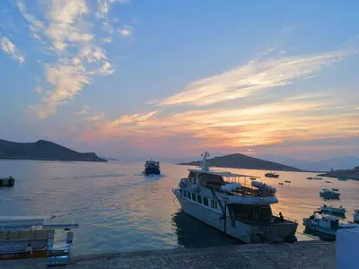 a group of boats docked in the water at sunset at Annas Houses in Halki