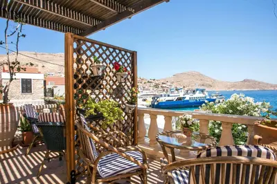 a balcony with chairs and a view of the water at Annas Houses in Halki